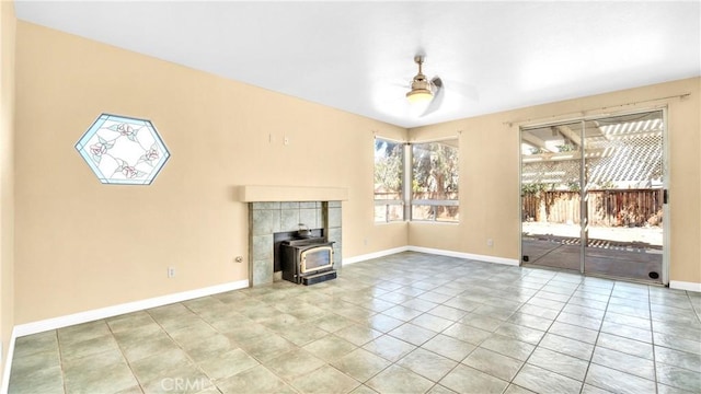 unfurnished living room with ceiling fan, tile patterned floors, and a wood stove