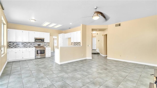 kitchen with appliances with stainless steel finishes, ceiling fan, white cabinets, and light tile patterned floors