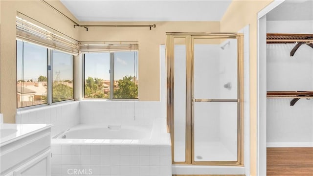 bathroom with independent shower and bath, vanity, and plenty of natural light