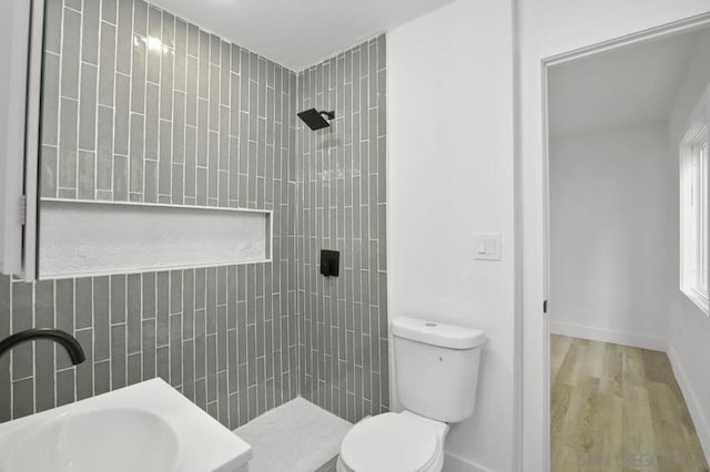 bathroom with toilet, a tile shower, hardwood / wood-style floors, and sink