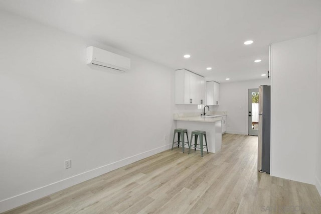 interior space with sink, light wood-type flooring, and a wall unit AC