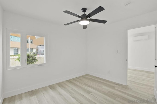 empty room featuring an AC wall unit, ceiling fan, and light hardwood / wood-style flooring