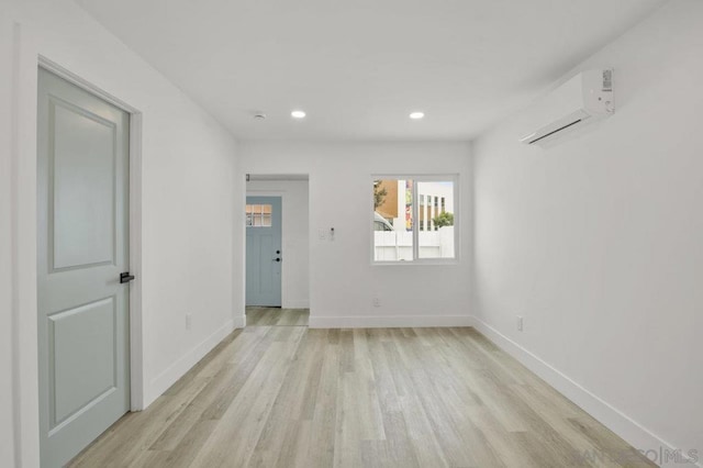 empty room featuring an AC wall unit and light hardwood / wood-style flooring