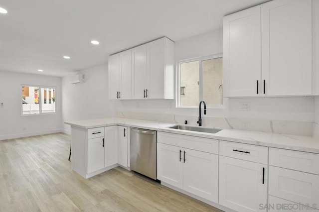 kitchen with sink, white cabinets, dishwasher, light hardwood / wood-style floors, and a wall unit AC