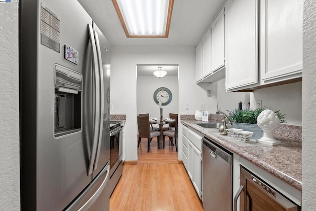 kitchen with white cabinets, stainless steel appliances, light wood-type flooring, and sink