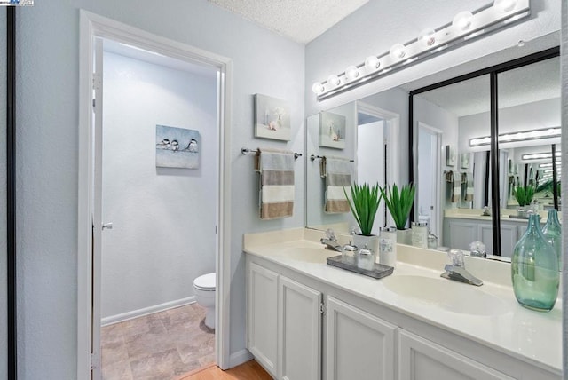 bathroom featuring toilet, a textured ceiling, and vanity