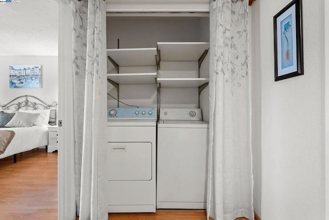 washroom featuring a textured ceiling, washing machine and clothes dryer, and hardwood / wood-style flooring