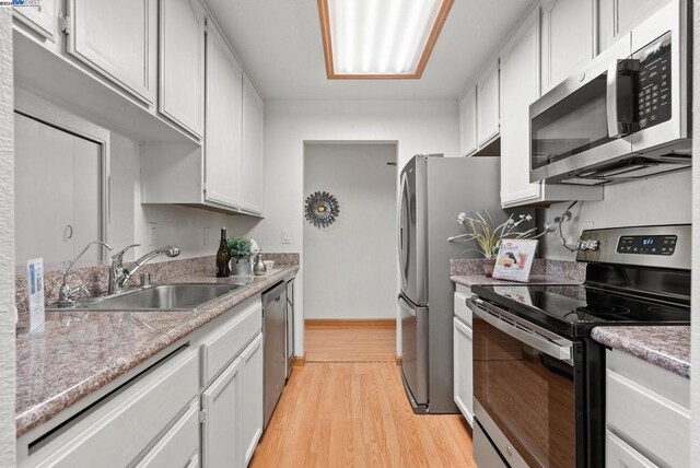 kitchen with sink, white cabinetry, light hardwood / wood-style floors, and appliances with stainless steel finishes