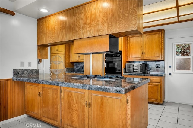 kitchen with premium range hood, light tile patterned flooring, stainless steel gas stovetop, oven, and kitchen peninsula