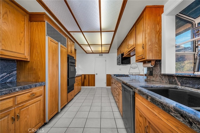 kitchen featuring light tile patterned flooring, gas cooktop, black dishwasher, dark stone counters, and backsplash