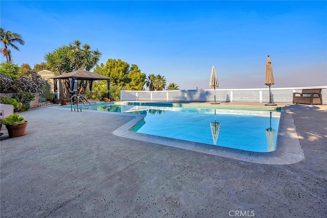 pool at dusk featuring a gazebo and a patio area