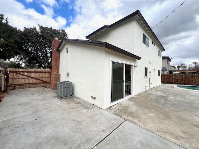 back of property with central AC unit, stucco siding, a fenced backyard, crawl space, and a patio