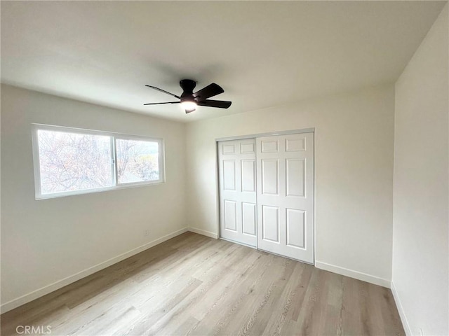 unfurnished bedroom with wood finished floors, baseboards, a closet, and ceiling fan