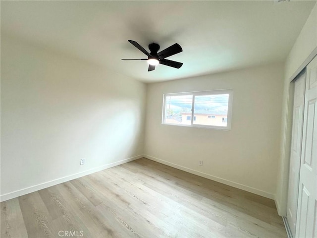 unfurnished bedroom featuring light wood-style flooring, a ceiling fan, baseboards, and a closet