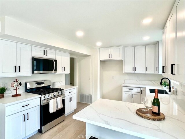 kitchen featuring light stone counters, appliances with stainless steel finishes, sink, and white cabinets