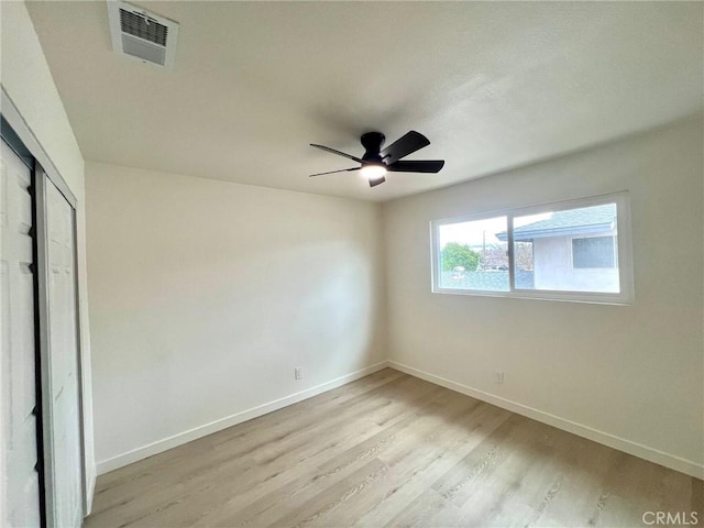 empty room featuring ceiling fan, visible vents, baseboards, and light wood-style flooring