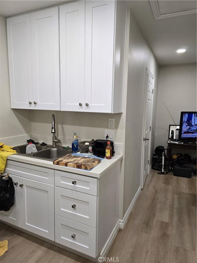 bar with sink, white cabinetry, and light hardwood / wood-style floors