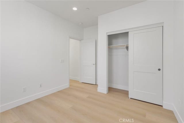 unfurnished bedroom with a closet and light hardwood / wood-style floors