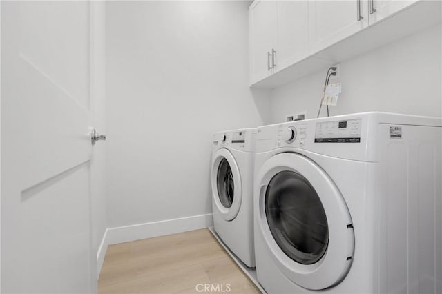 clothes washing area featuring independent washer and dryer, cabinets, and light hardwood / wood-style flooring