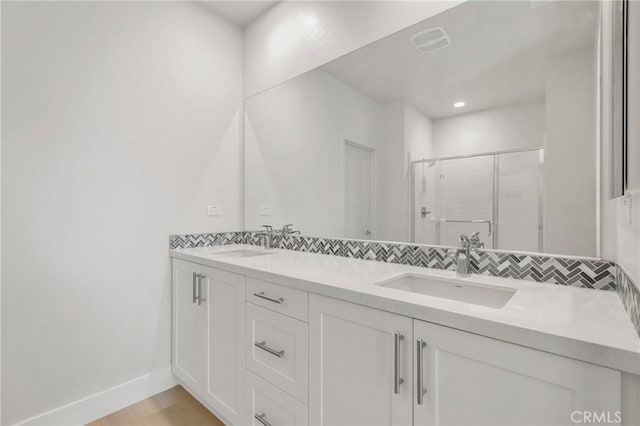 bathroom with backsplash, a shower with shower door, and vanity