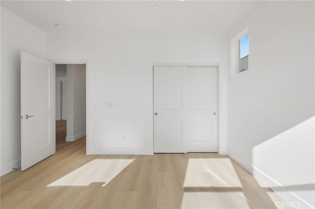 unfurnished bedroom with a closet and light hardwood / wood-style flooring