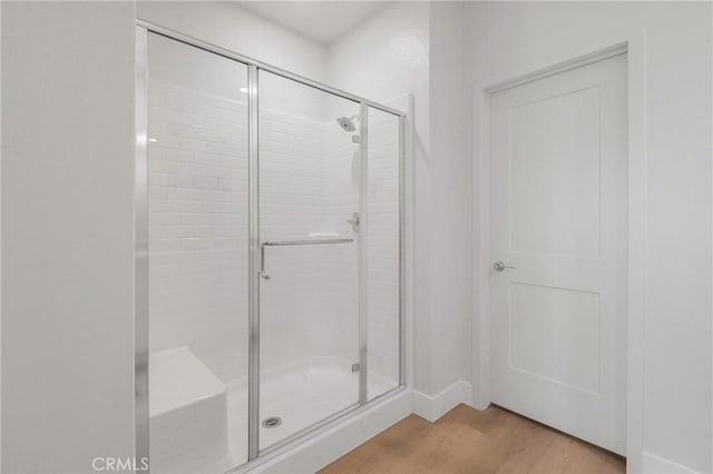 bathroom with a shower with door and hardwood / wood-style flooring