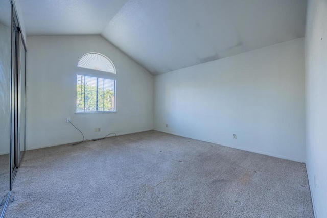 unfurnished room featuring vaulted ceiling and carpet