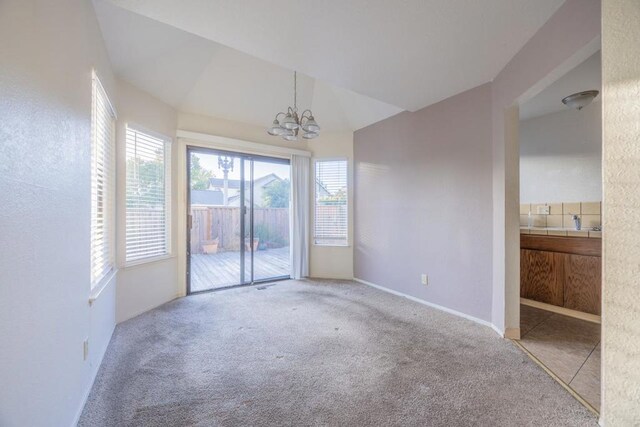 carpeted spare room with lofted ceiling and a notable chandelier