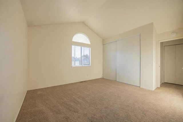 carpeted spare room with vaulted ceiling