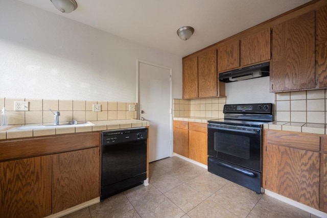 kitchen with black appliances, light tile patterned floors, tile countertops, sink, and tasteful backsplash