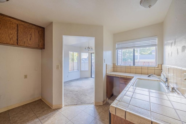 kitchen featuring sink, tile counters, an inviting chandelier, and light tile patterned floors