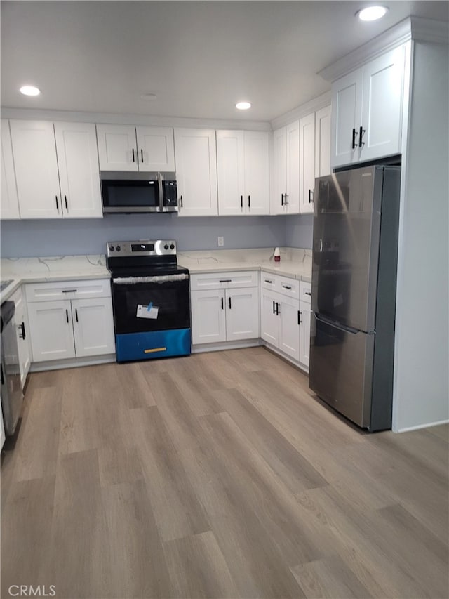 kitchen with white cabinets, light stone countertops, stainless steel appliances, and light hardwood / wood-style floors