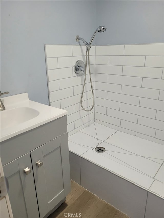 bathroom featuring wood-type flooring, vanity, and a tile shower