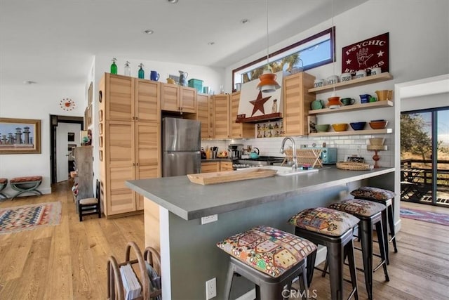 kitchen featuring open shelves, light wood-type flooring, a peninsula, and freestanding refrigerator