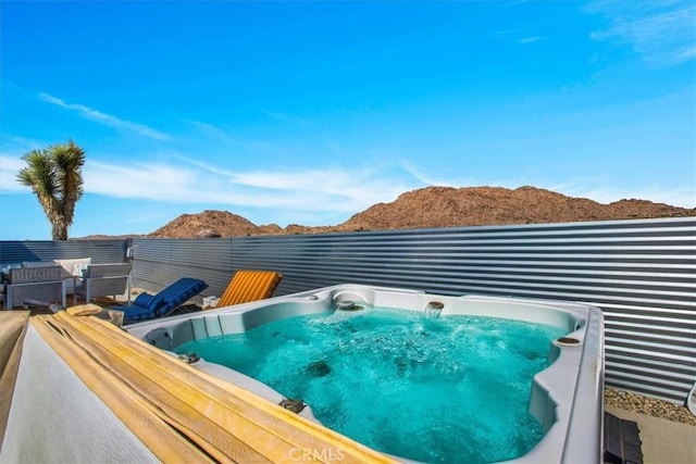 view of swimming pool with a mountain view and a hot tub