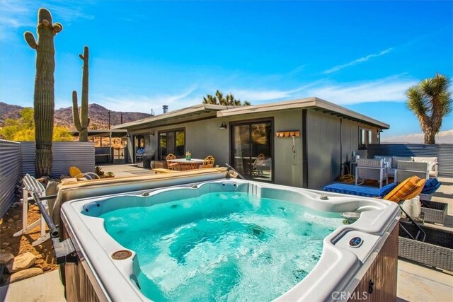 view of swimming pool with a fenced backyard, a mountain view, and a hot tub