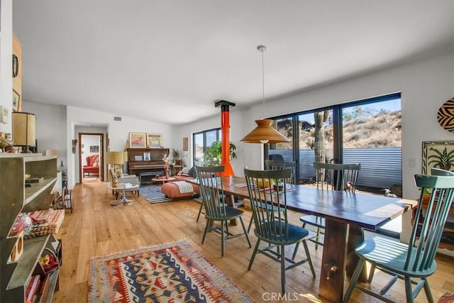 dining area featuring light wood-type flooring and vaulted ceiling