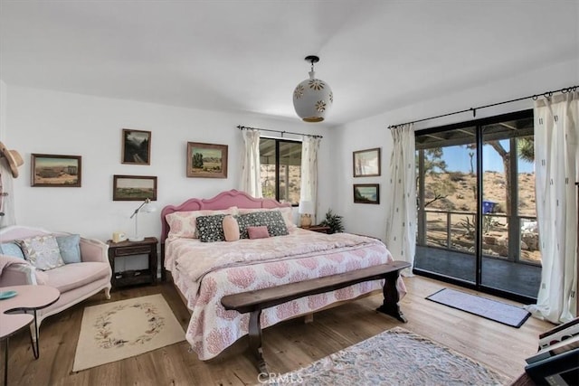 bedroom with access to outside and wood finished floors