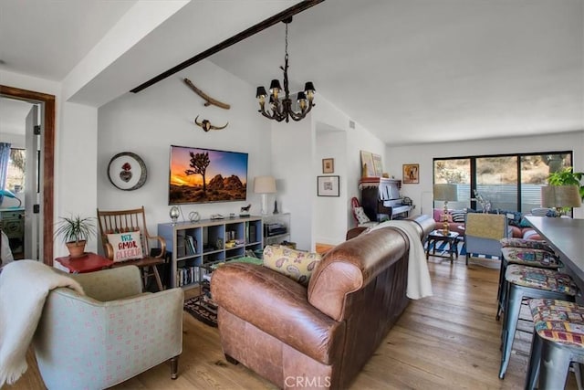 living room with wood finished floors, an inviting chandelier, and vaulted ceiling