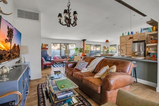 living room with a chandelier, visible vents, light wood-style flooring, and baseboards