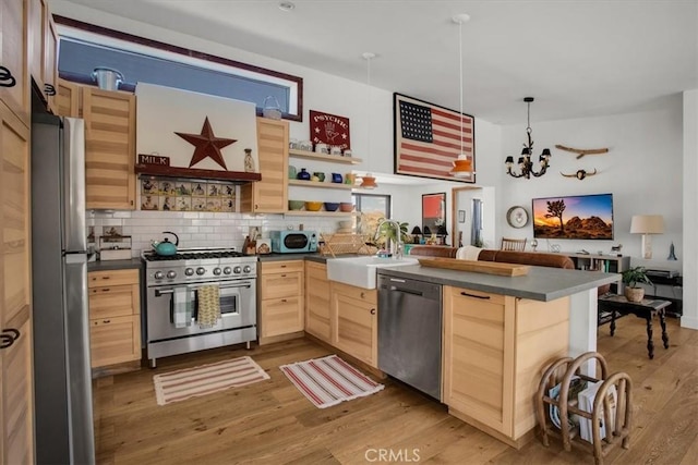 kitchen with dark countertops, a sink, light brown cabinets, appliances with stainless steel finishes, and open shelves