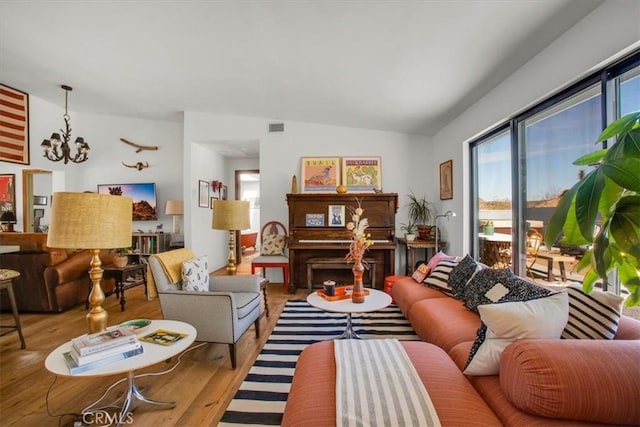 living area featuring visible vents, lofted ceiling, an inviting chandelier, and wood finished floors