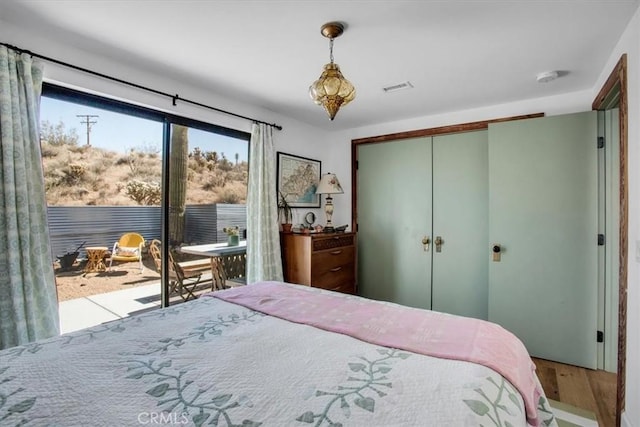 bedroom featuring a closet, visible vents, access to outside, and wood finished floors