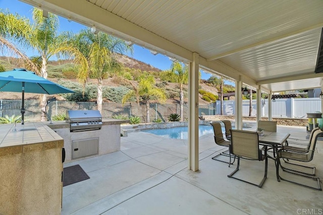 view of patio / terrace featuring exterior kitchen, grilling area, a fenced in pool, and sink