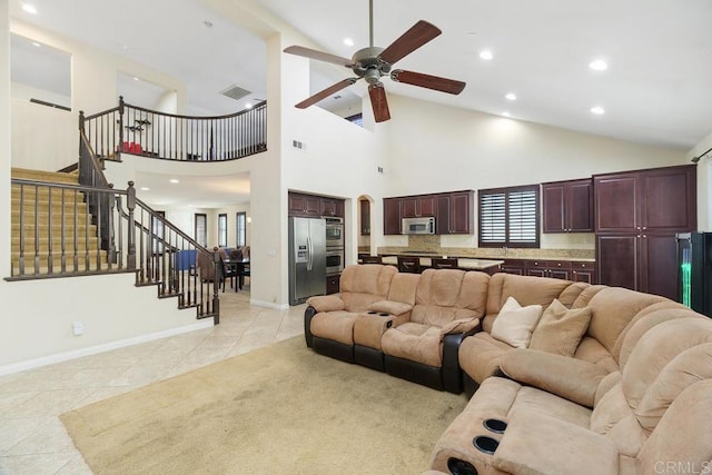 living room with light tile patterned floors, ceiling fan, and a high ceiling