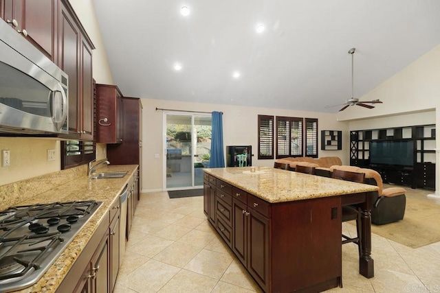 kitchen with sink, appliances with stainless steel finishes, a kitchen island, a kitchen bar, and vaulted ceiling