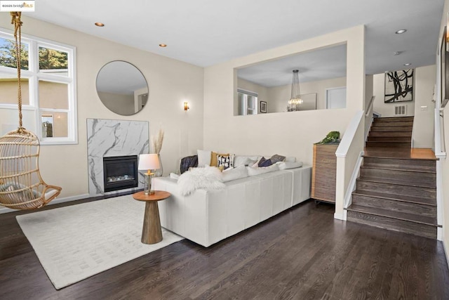 living room featuring a high end fireplace and dark hardwood / wood-style flooring