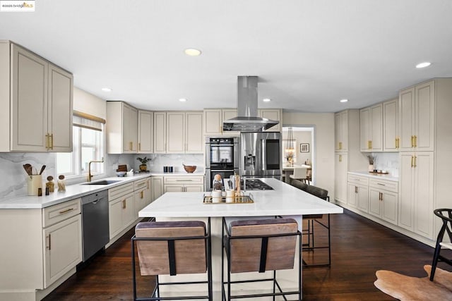 kitchen featuring sink, a center island, a kitchen breakfast bar, island exhaust hood, and appliances with stainless steel finishes