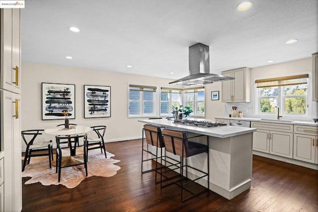 kitchen with island range hood, a center island, plenty of natural light, a breakfast bar area, and sink