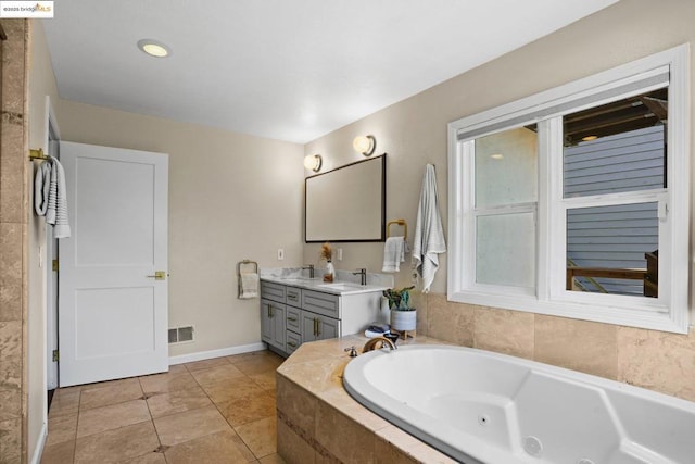 bathroom with tile patterned floors, tiled tub, and vanity